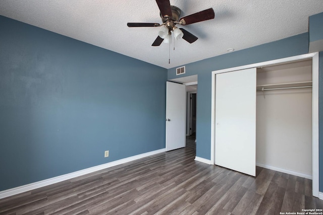 unfurnished bedroom featuring a closet, a textured ceiling, dark hardwood / wood-style floors, and ceiling fan