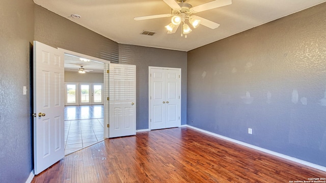 unfurnished bedroom with ceiling fan, hardwood / wood-style floors, and french doors