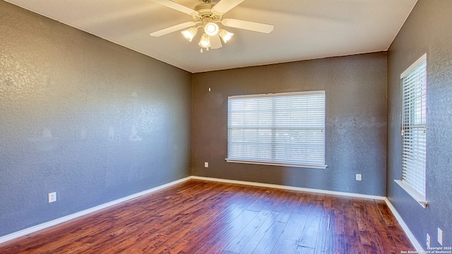 spare room with ceiling fan, dark wood-type flooring, and a healthy amount of sunlight