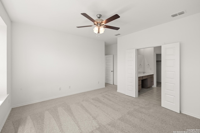 unfurnished bedroom with connected bathroom, light colored carpet, and ceiling fan