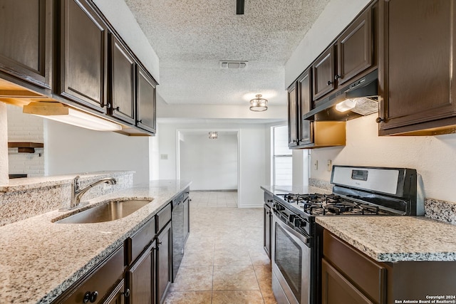 kitchen with sink, gas range, a textured ceiling, dark brown cabinets, and light stone counters