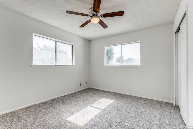 unfurnished bedroom featuring a textured ceiling, carpet floors, and multiple windows