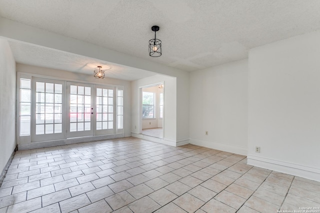 spare room featuring light tile patterned floors and a textured ceiling