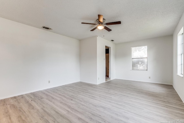 empty room featuring ceiling fan, light wood-type flooring, and a textured ceiling