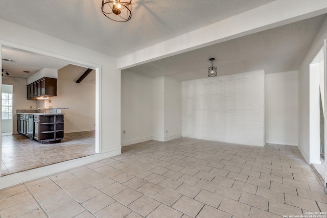 tiled spare room with beam ceiling and a textured ceiling