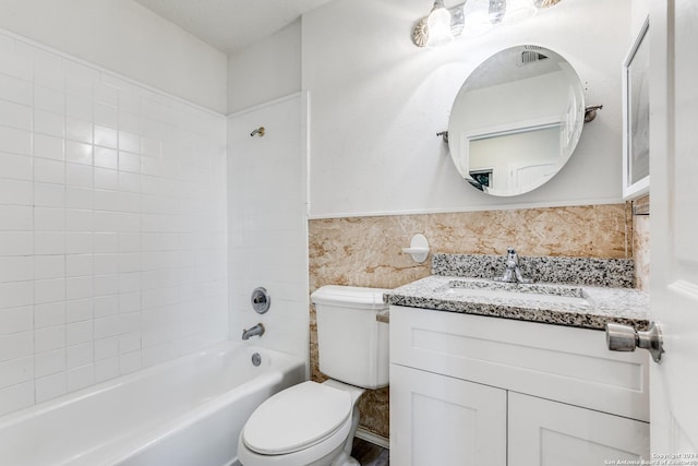 full bathroom with a textured ceiling, vanity, toilet, and tiled shower / bath