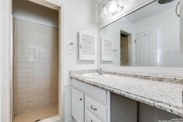 bathroom featuring tiled shower and vanity