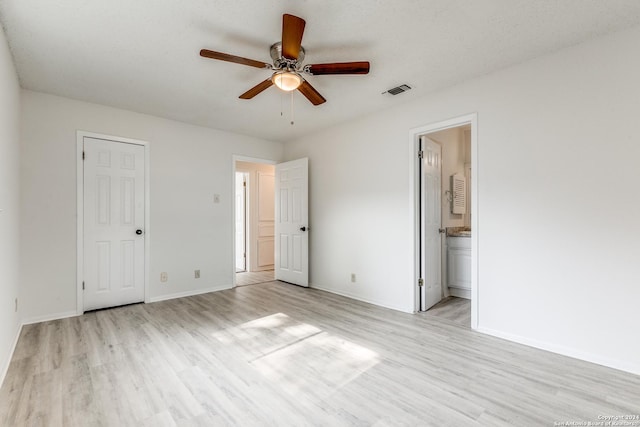 unfurnished bedroom featuring a textured ceiling, light wood-type flooring, ensuite bath, and ceiling fan