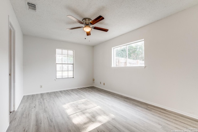 spare room featuring a healthy amount of sunlight, a textured ceiling, and light wood-type flooring