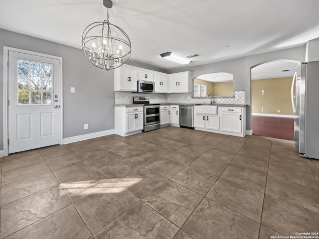 kitchen with white cabinets, stainless steel appliances, hanging light fixtures, and a chandelier