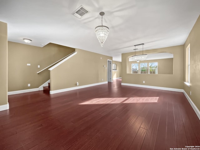 unfurnished living room with dark wood-type flooring and a notable chandelier