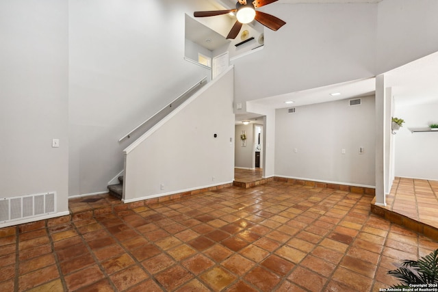 unfurnished living room with ceiling fan and a high ceiling