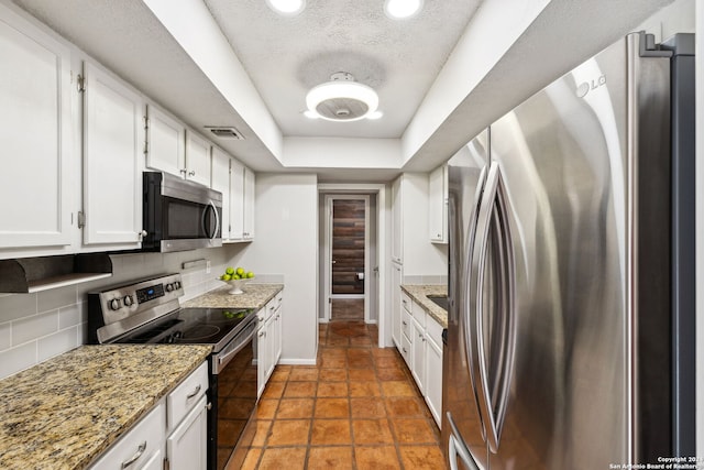 kitchen featuring backsplash, a textured ceiling, stone countertops, white cabinetry, and stainless steel appliances