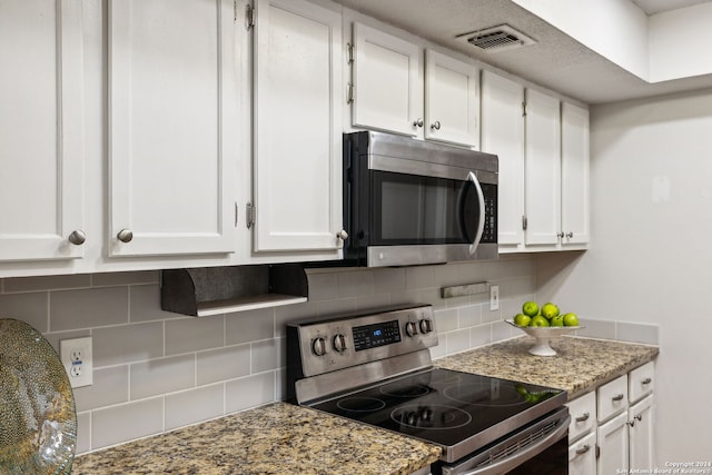 kitchen featuring appliances with stainless steel finishes, tasteful backsplash, white cabinetry, and light stone counters