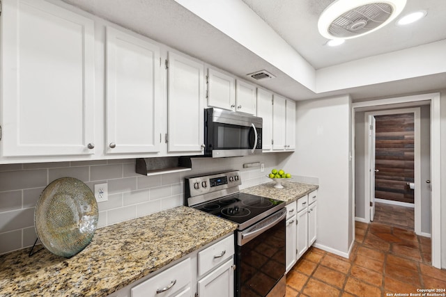 kitchen featuring white cabinets, appliances with stainless steel finishes, decorative backsplash, and light stone counters