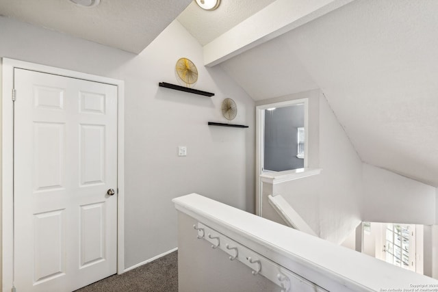 hallway with lofted ceiling with beams and dark colored carpet