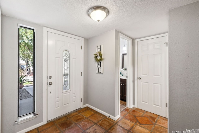 foyer entrance featuring a textured ceiling and dark tile patterned floors