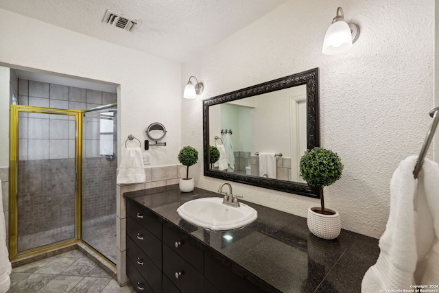 bathroom featuring a shower with door, vanity, and a textured ceiling