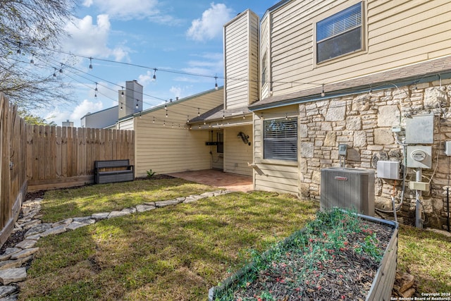 back of house featuring central air condition unit, a patio area, and a lawn