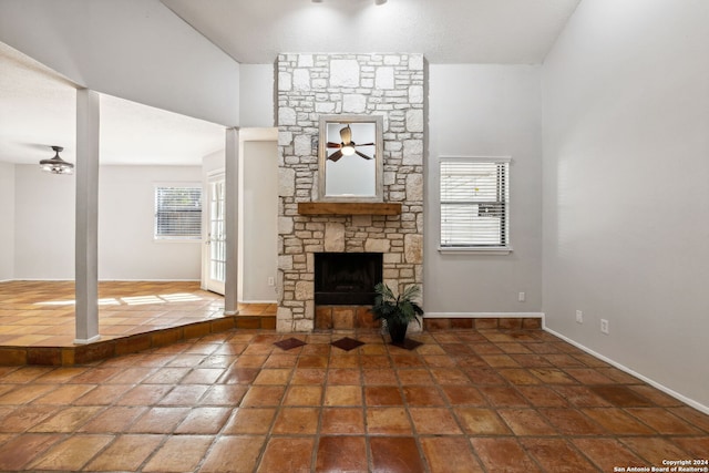 unfurnished living room with a stone fireplace, a towering ceiling, and a wealth of natural light