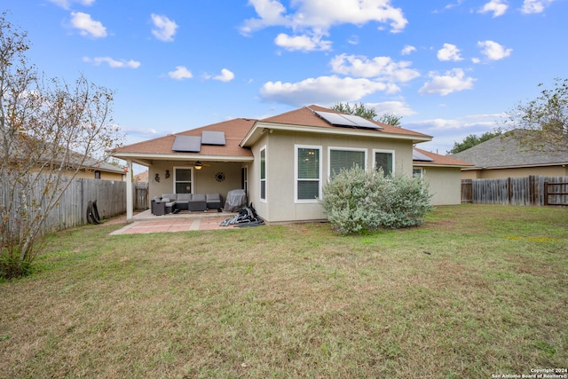 rear view of house with outdoor lounge area, a yard, a patio, and solar panels