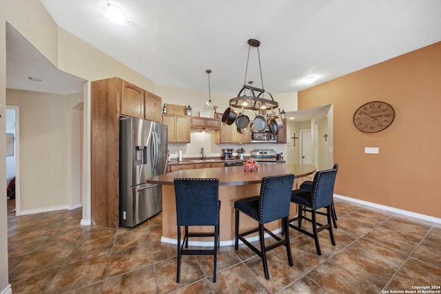 kitchen with a kitchen breakfast bar, stainless steel appliances, sink, decorative light fixtures, and a kitchen island