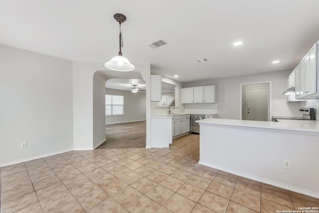 kitchen with kitchen peninsula, light tile patterned floors, white cabinetry, and sink