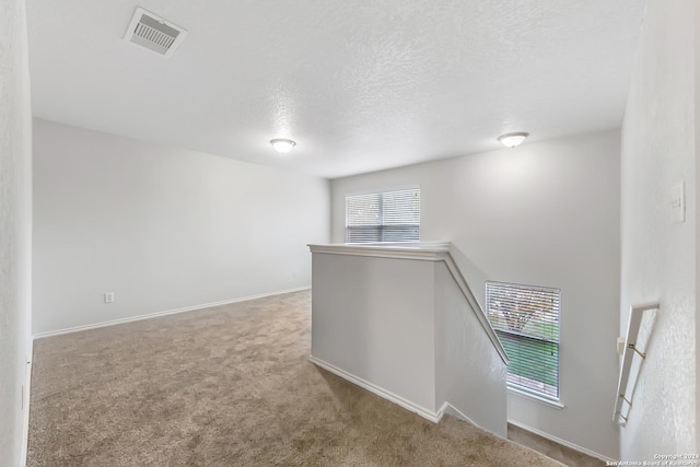 hall featuring a textured ceiling and light carpet