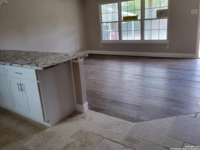 kitchen with white cabinetry, light hardwood / wood-style flooring, and light stone countertops