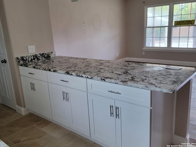 kitchen featuring white cabinets and light stone counters