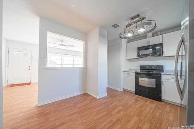 kitchen with white cabinets, light wood-type flooring, light stone counters, and black appliances