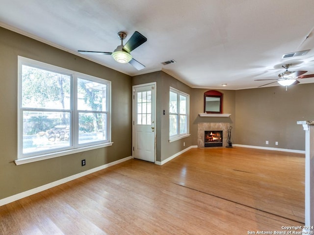 unfurnished living room featuring crown molding, plenty of natural light, ceiling fan, and light wood-type flooring