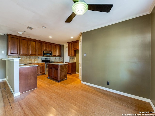 kitchen with sink, a center island, stainless steel appliances, tasteful backsplash, and light hardwood / wood-style floors