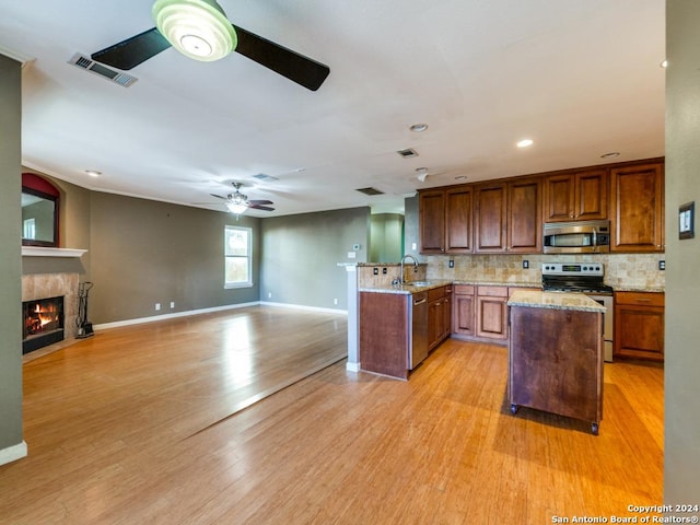 kitchen featuring sink, light hardwood / wood-style flooring, tasteful backsplash, light stone counters, and stainless steel appliances