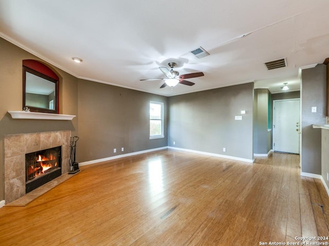 unfurnished living room featuring a tile fireplace, ceiling fan, light hardwood / wood-style flooring, and ornamental molding