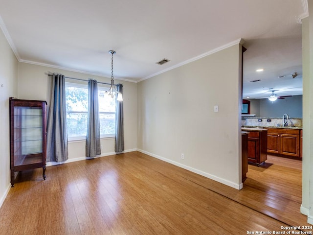 spare room featuring sink, light hardwood / wood-style floors, ceiling fan with notable chandelier, and ornamental molding