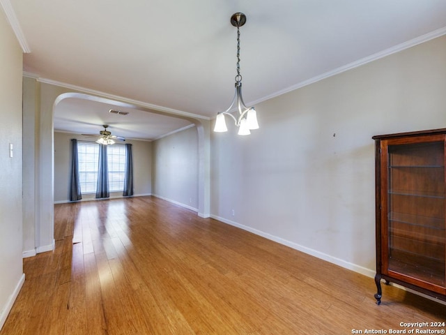 spare room featuring hardwood / wood-style floors, ceiling fan with notable chandelier, and crown molding