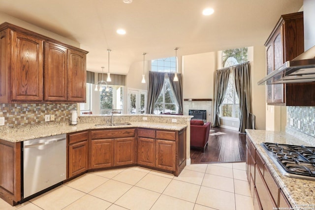 kitchen featuring backsplash, wall chimney range hood, hanging light fixtures, sink, and appliances with stainless steel finishes