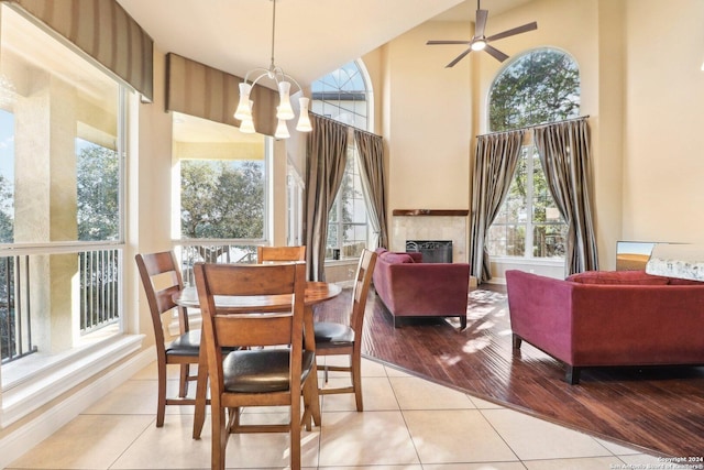 dining room with ceiling fan with notable chandelier, high vaulted ceiling, and light hardwood / wood-style flooring