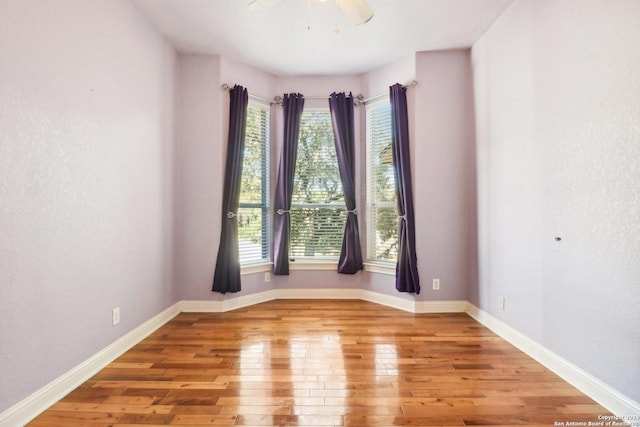 spare room featuring ceiling fan, a healthy amount of sunlight, and light wood-type flooring