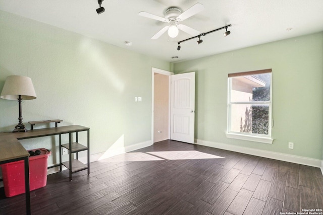 unfurnished room featuring rail lighting, ceiling fan, and dark wood-type flooring