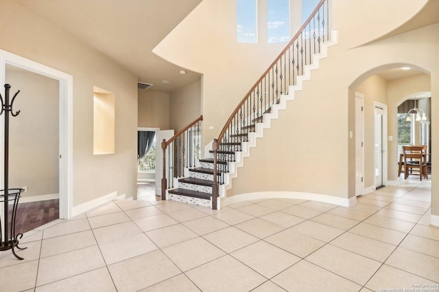 staircase featuring a towering ceiling, tile patterned floors, and a healthy amount of sunlight