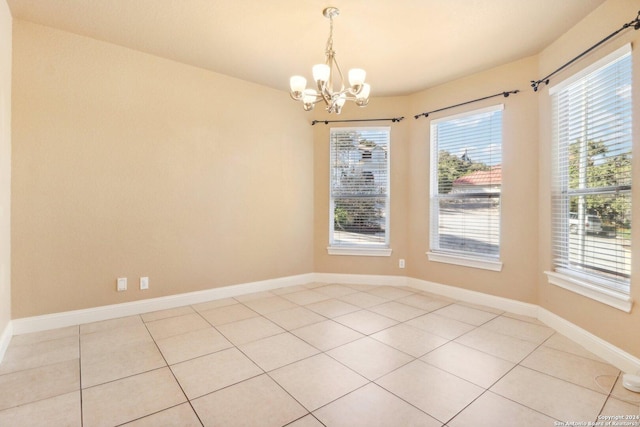 spare room featuring light tile patterned floors, an inviting chandelier, and plenty of natural light