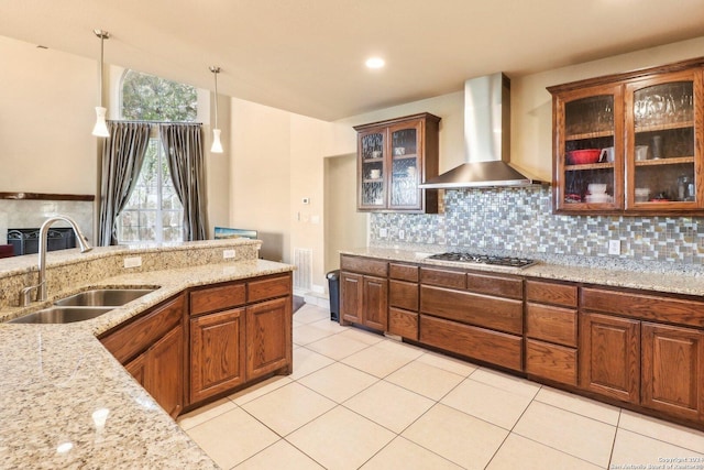 kitchen featuring light stone countertops, sink, wall chimney exhaust hood, pendant lighting, and decorative backsplash