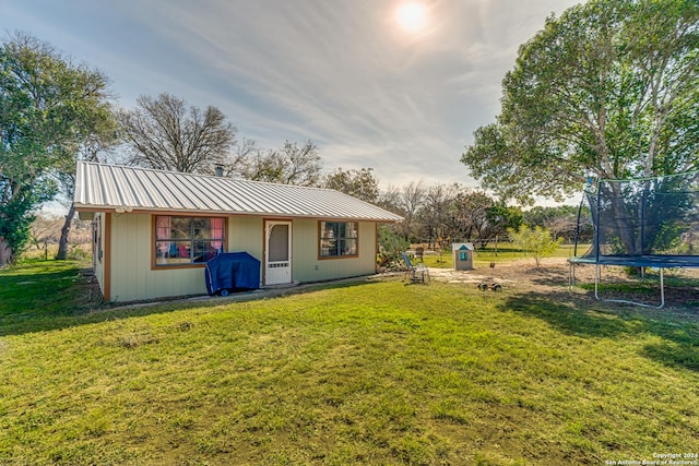 back of house featuring a yard and a trampoline