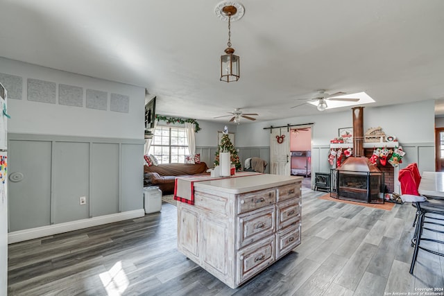 kitchen featuring a barn door, a kitchen island, hanging light fixtures, and wood-type flooring