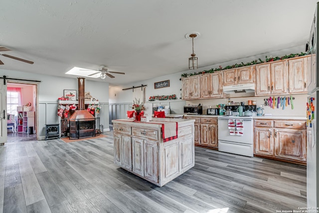 kitchen featuring decorative light fixtures, a barn door, light wood-type flooring, white electric range oven, and a kitchen island