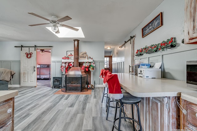 kitchen featuring a kitchen breakfast bar, a barn door, light hardwood / wood-style floors, and ceiling fan