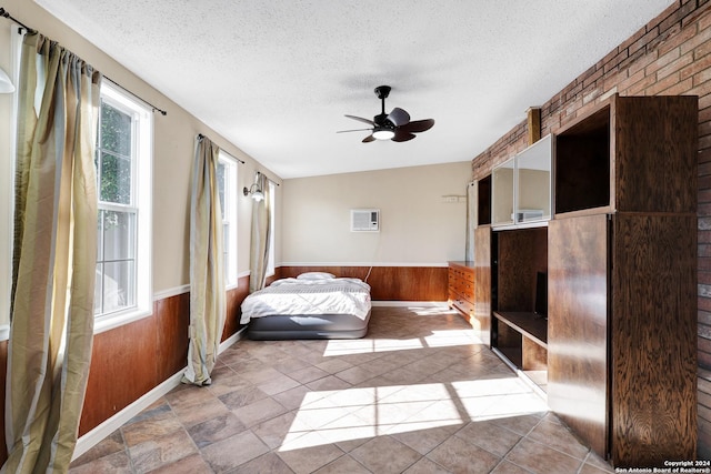 unfurnished bedroom with lofted ceiling, an AC wall unit, wooden walls, ceiling fan, and a textured ceiling