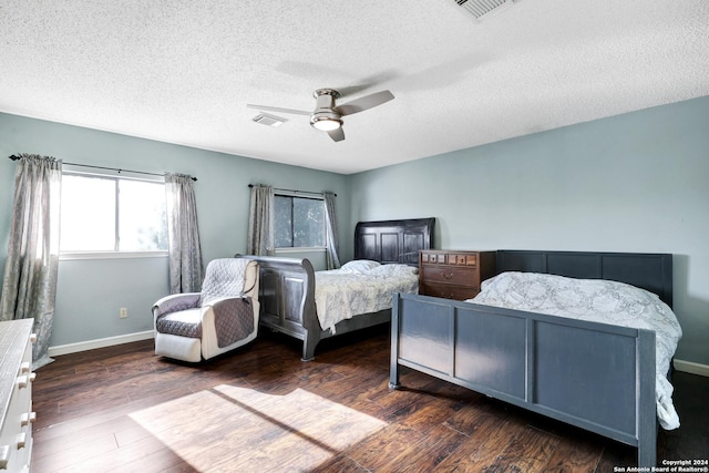 bedroom with ceiling fan, dark wood-type flooring, and a textured ceiling